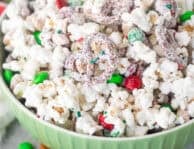 Bowl of Christmas popcorn with mini pretzels, red and green M&M's, roasted peanuts and festive sprinkles.