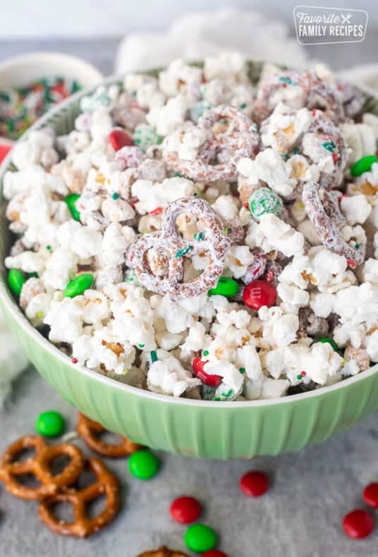 Bowl of Christmas popcorn with mini pretzels, red and green M&M's, roasted peanuts and festive sprinkles.