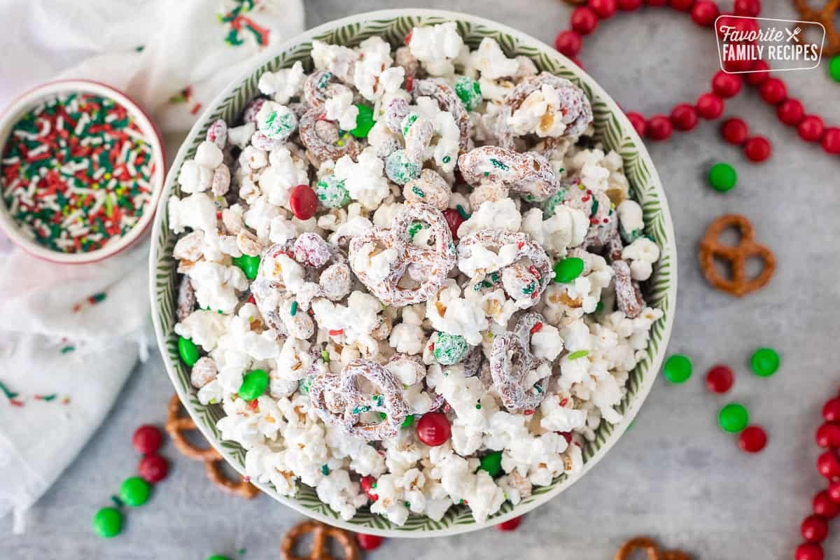 Bowl of Christmas Crunch popcorn with mini pretzels, red and green M&M's, roasted peanuts and festive sprinkles.