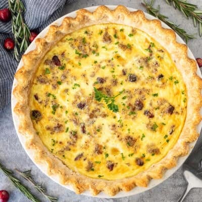 Baked Christmas Quiche garnished with parsley. Spatula on the side.
