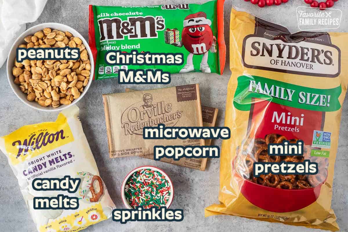 Ingredients in Christmas crunch popcorn: Microwave popcorn, candy melts, pretzels, m&ms, peanuts, and sprinkles