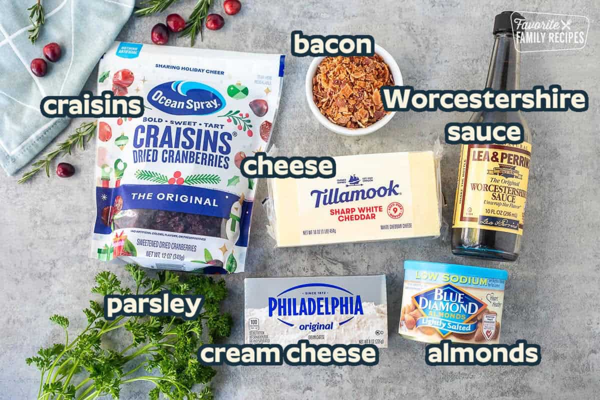 Ingredients to make cranberry cheese ball including raisins, sharp white cheddar, bacon, Worcestershire sauce, almonds, parsley, and cream cheese.