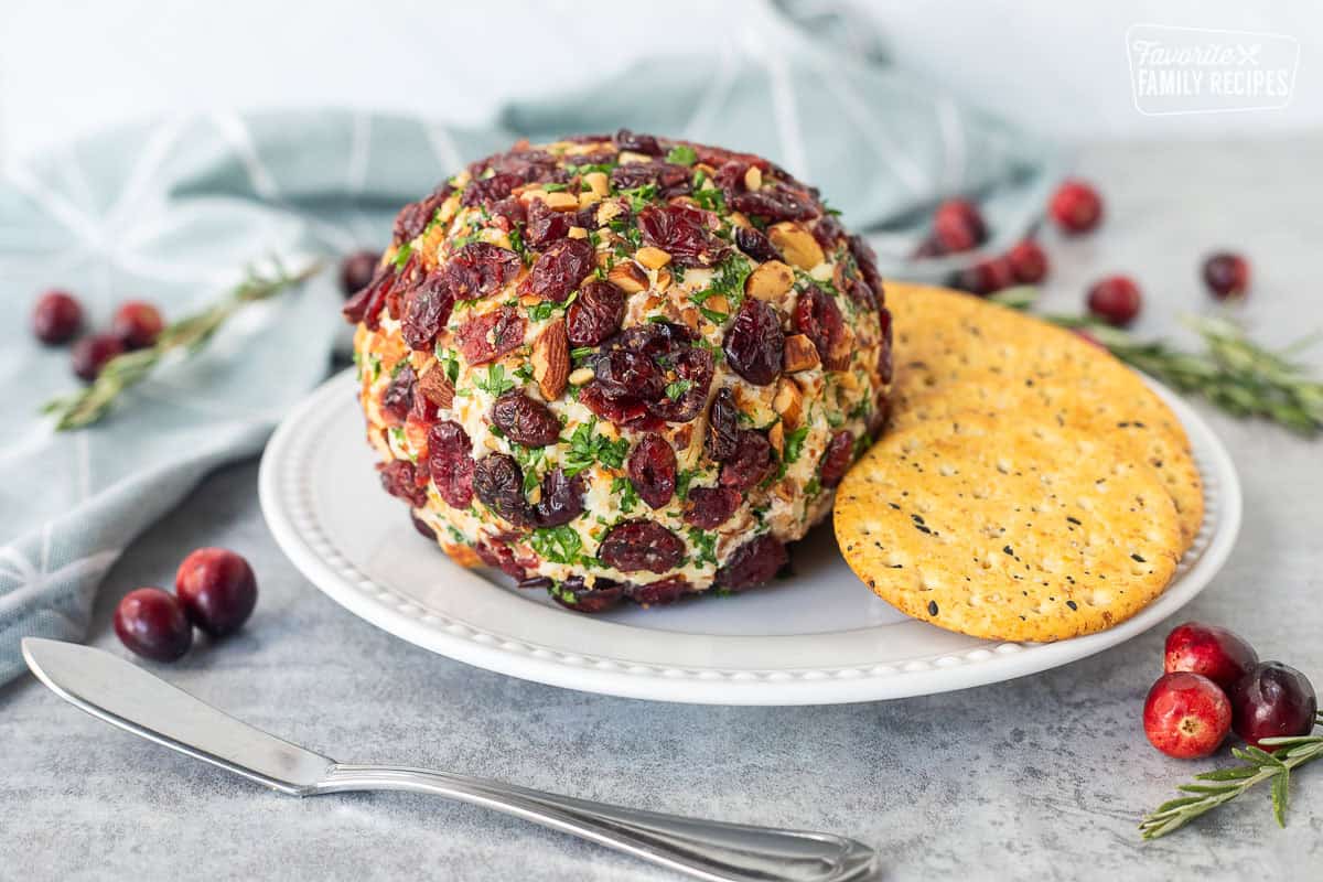 Cranberry cheese ball on a plate next to crackers.