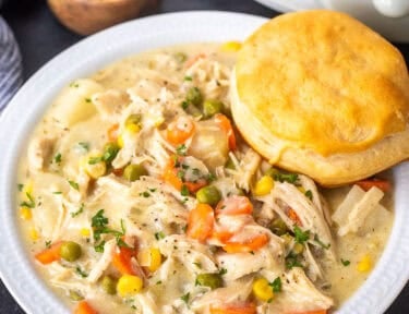 Bowl of crock pot chicken pot pie with a biscuit resting on top.