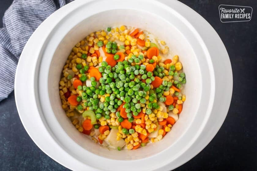 Chicken, seasonings, potatoes, corn, carrots, celery, and peas in a crock pot.