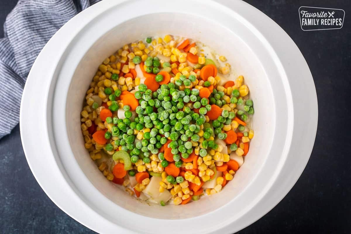 Chicken, seasonings, potatoes, corn, carrots, celery, and peas in a crock pot.