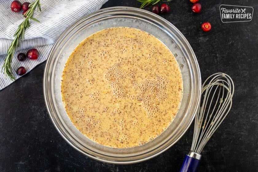 Glass bowl with egg mixture and whisk on the side.