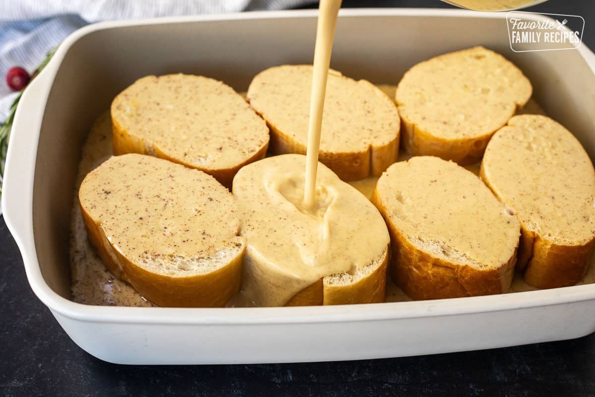 Pouring eggnog egg mixture on top of sliced pieces of French bread in a baking dish.