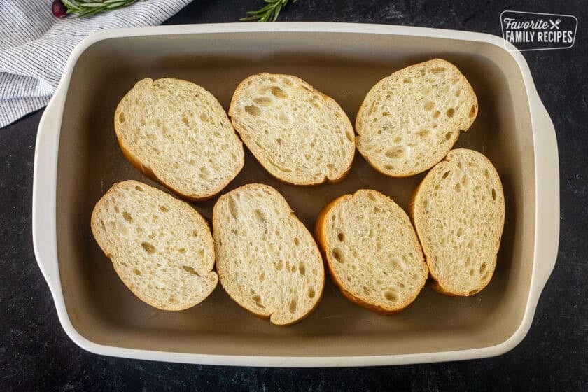 Sliced French loaf bread in a baking dish.
