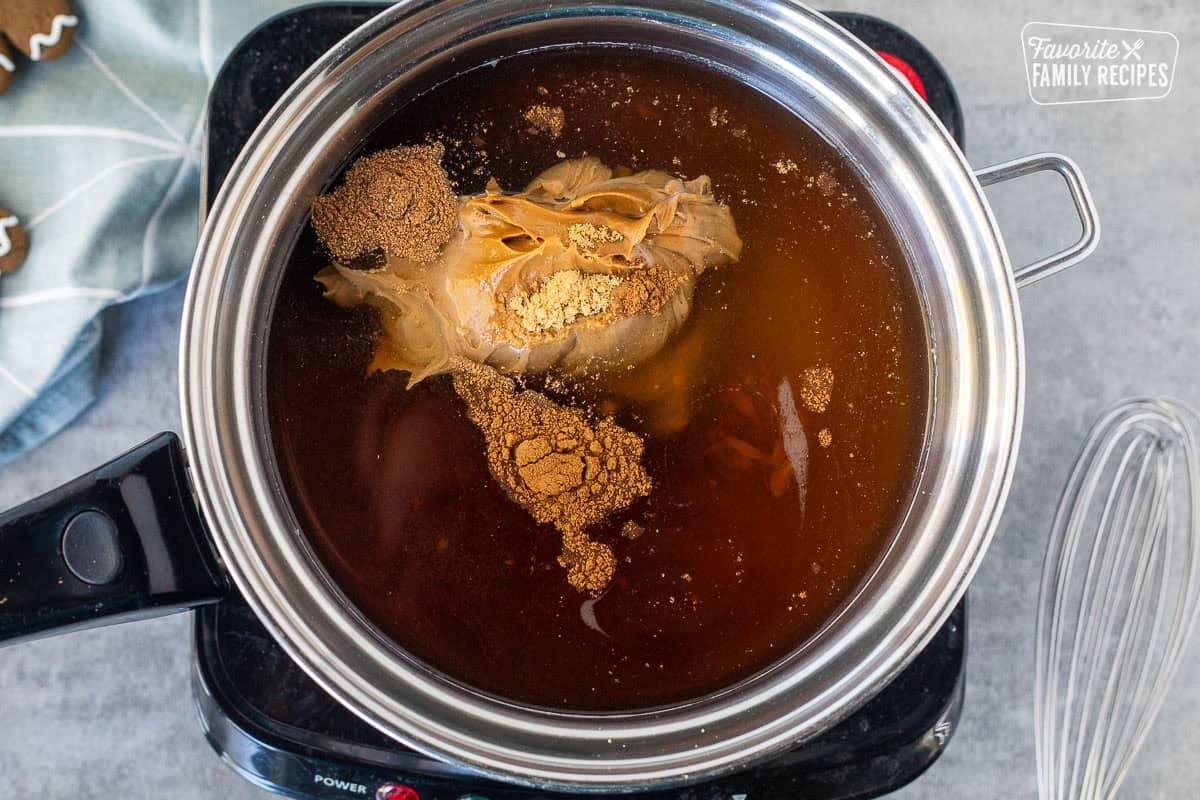 Saucepan with ingredients to make gingerbread syrup on an electric burner.