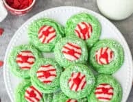 Plate of Grinch cookies with melted Candy Cane Kisses and red heart sprinkles.