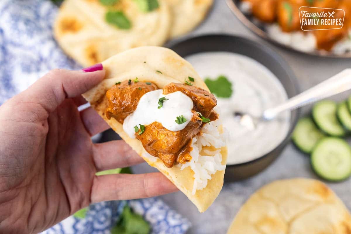 Naan bread with Chicken Tikka Masala and Raita sauce on top.