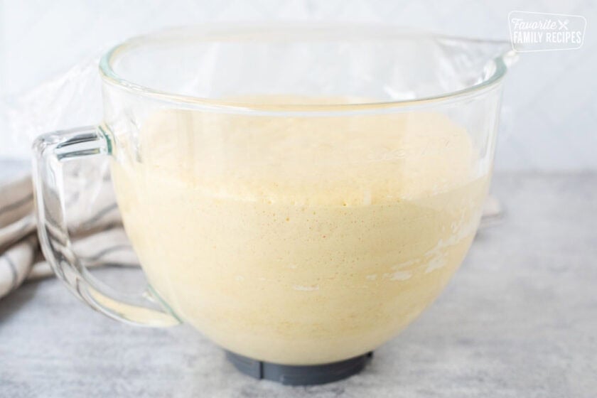 Glass bowl of Sally Lunn Bread dough rising and doubled in size.