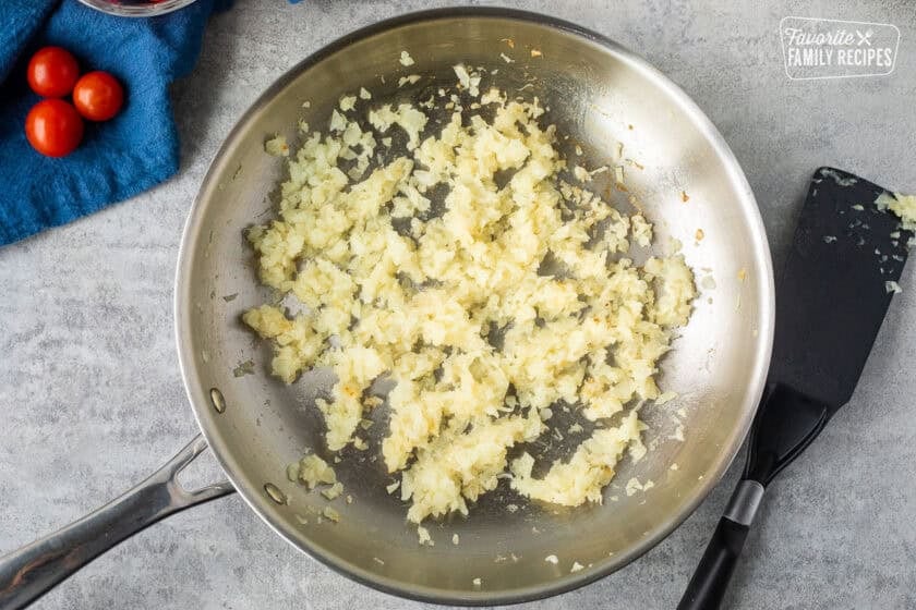 Skillet with grilled onions and spatula on the side.