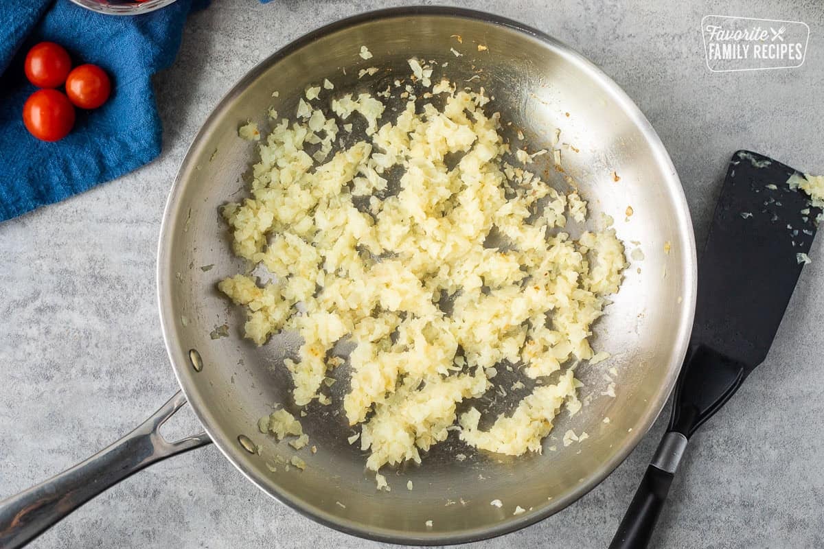 Skillet with grilled onions and spatula on the side.
