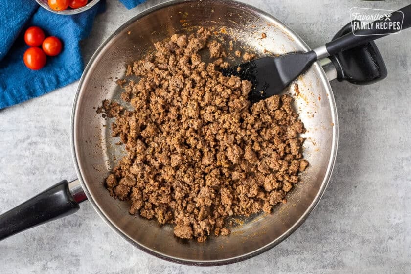 Skillet with burger mixture and spatula.