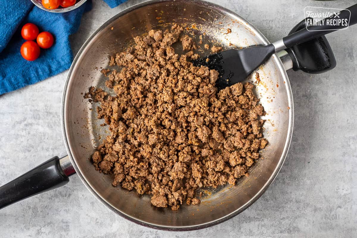 Skillet with burger mixture and spatula.