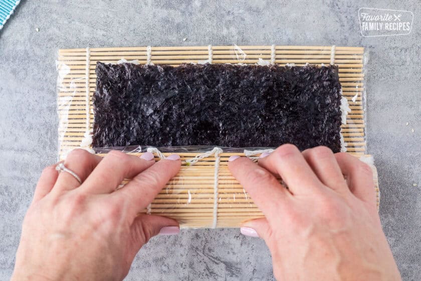 Rolling California roll sushi with bamboo mat.