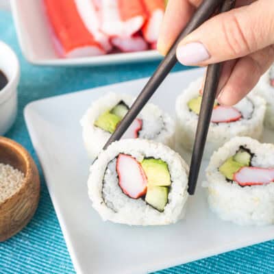 Picking up a California roll with chopsticks.