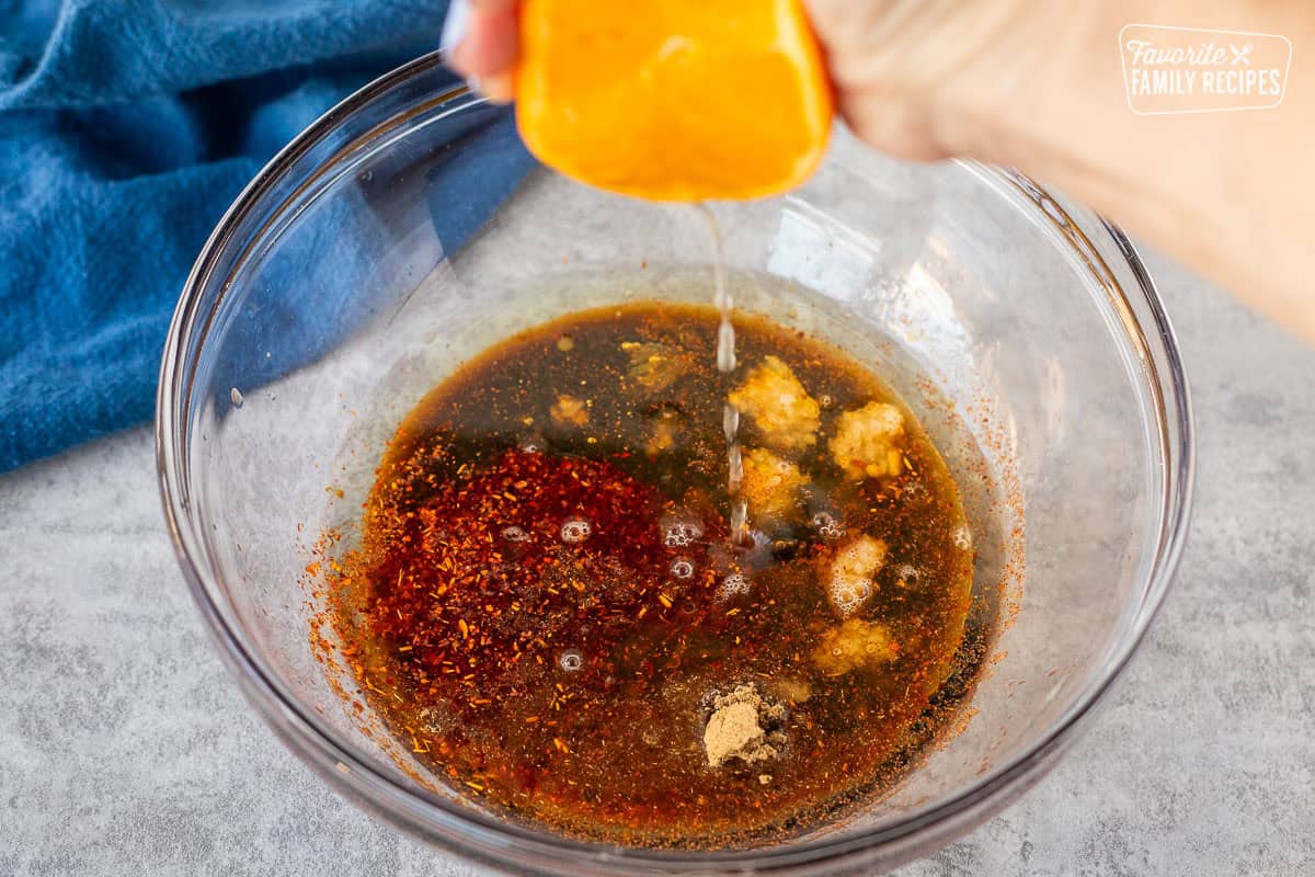 Squeezing fresh orange juice into bowl with other chicken fajita marinade ingredients.
