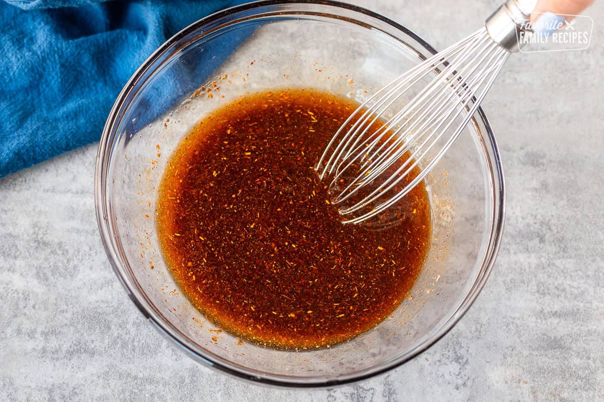 Whisking chicken fajita marinade together in a bowl with a whisk.