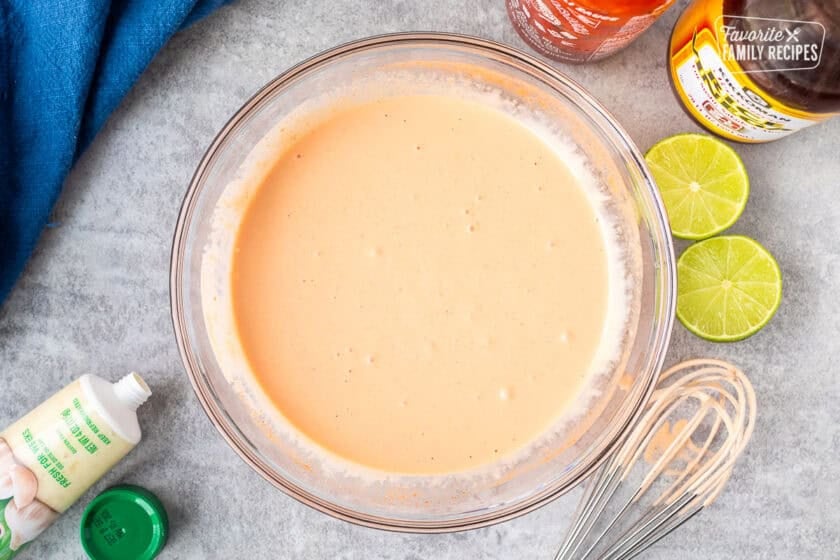 Sriracha mayo in a glass bowl with whisk on the side.