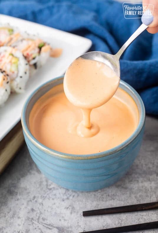 Drizzling easy sriracha mayo from a spoon into a bowl.