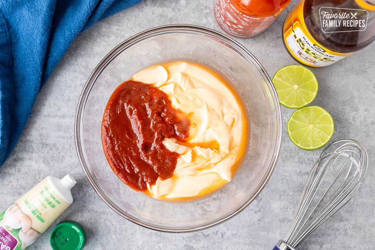 Mixing bowl with ingredients of easy sriracha mayo including Japanese mayo, sriracha hot chili sauce, garlic paste, rice vinegar, salt, sugar and lime juice.