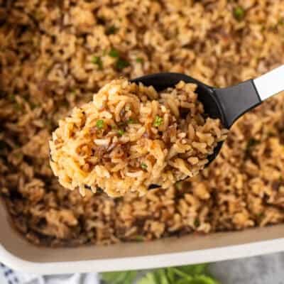 French onion rice in a large serving spoon over casserole dish.