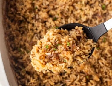 French onion rice in a large serving spoon over casserole dish.
