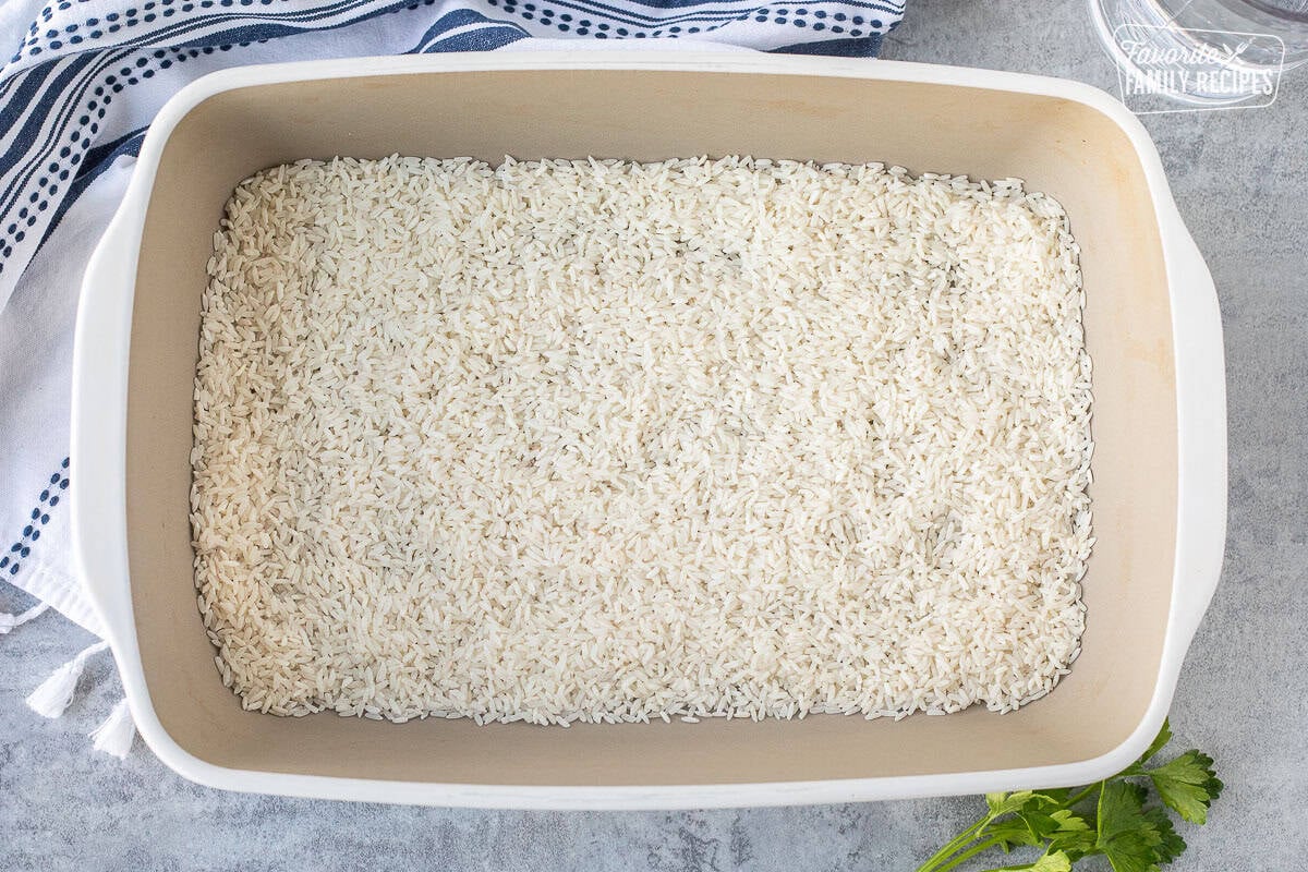 Baking dish with uncooked white rice on the bottom to make French Onion Rice.