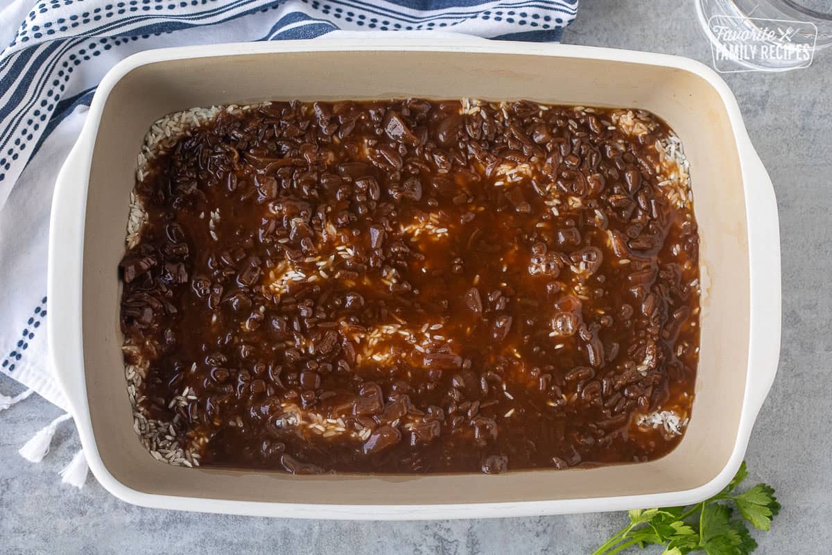 Condensed French onion soup poured over rice in a baking dish.
