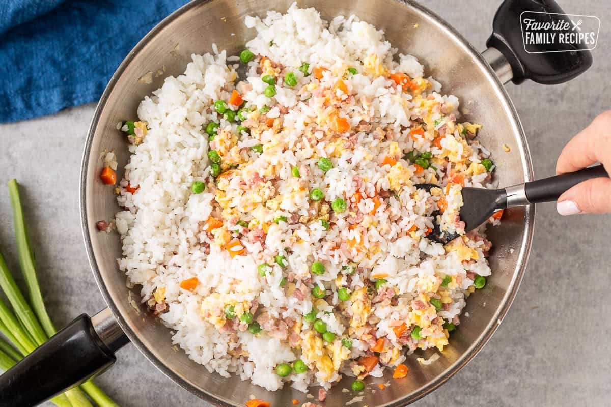 Stirring cold rice into skillet of ham, egg and vegetables.