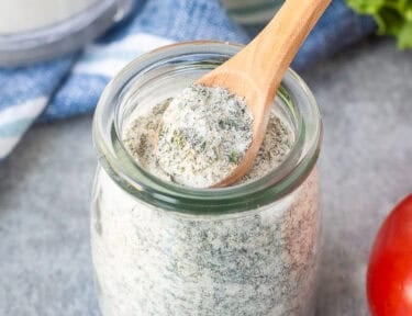 Hidden Valley Ranch Dressing Mix in a jar with a spoon.