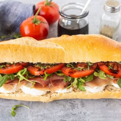 Prosciutto sandwich on Demi French bread with mozzarella cheese, prosciutto, arugula, tomatoes, basil and balsamic glaze.