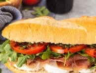 Prosciutto sandwich on Demi French bread with mozzarella cheese, prosciutto, arugula, tomatoes, basil and balsamic glaze.