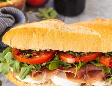 Prosciutto sandwich on Demi French bread with mozzarella cheese, prosciutto, arugula, tomatoes, basil and balsamic glaze.