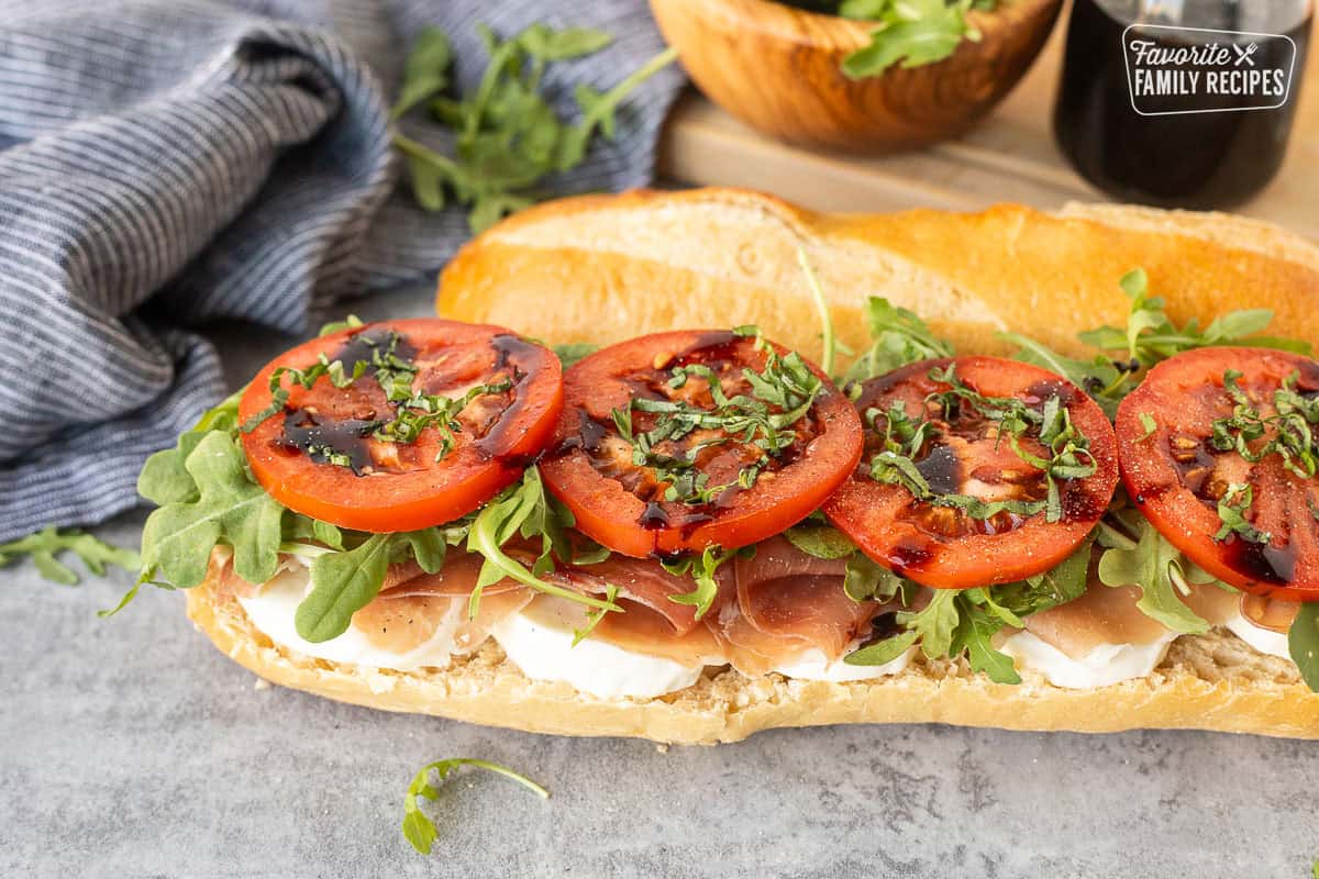 Prosciutto sandwich on French bread with mozzarella cheese, prosciutto, arugula, tomatoes, basil and balsamic glaze.