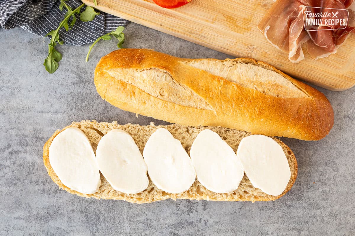 Demi French bread cut in half with a layer of fresh thick cut mozzarella cheese.