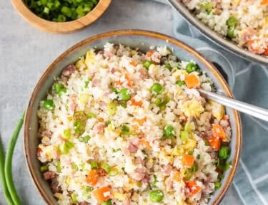 Bowl of cauliflower fried rice next to skillet.