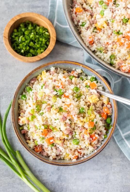 Bowl of cauliflower fried rice next to skillet.