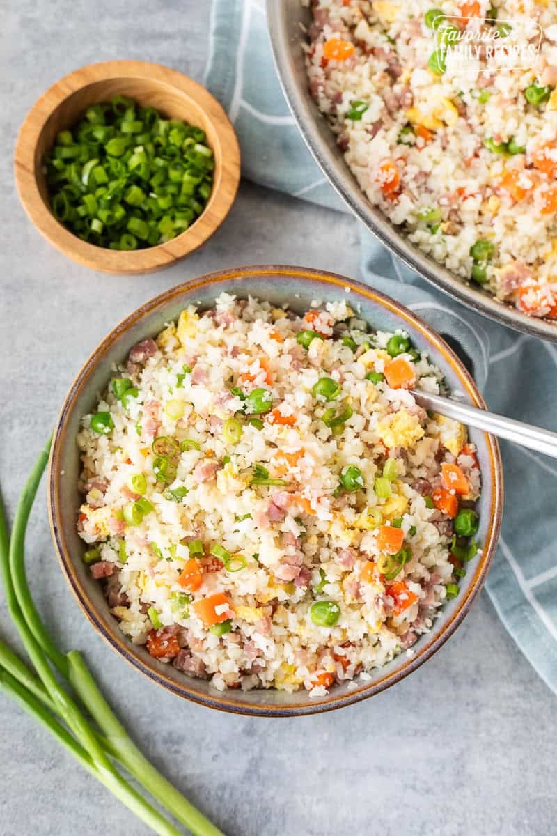 Bowl of cauliflower fried rice next to skillet.
