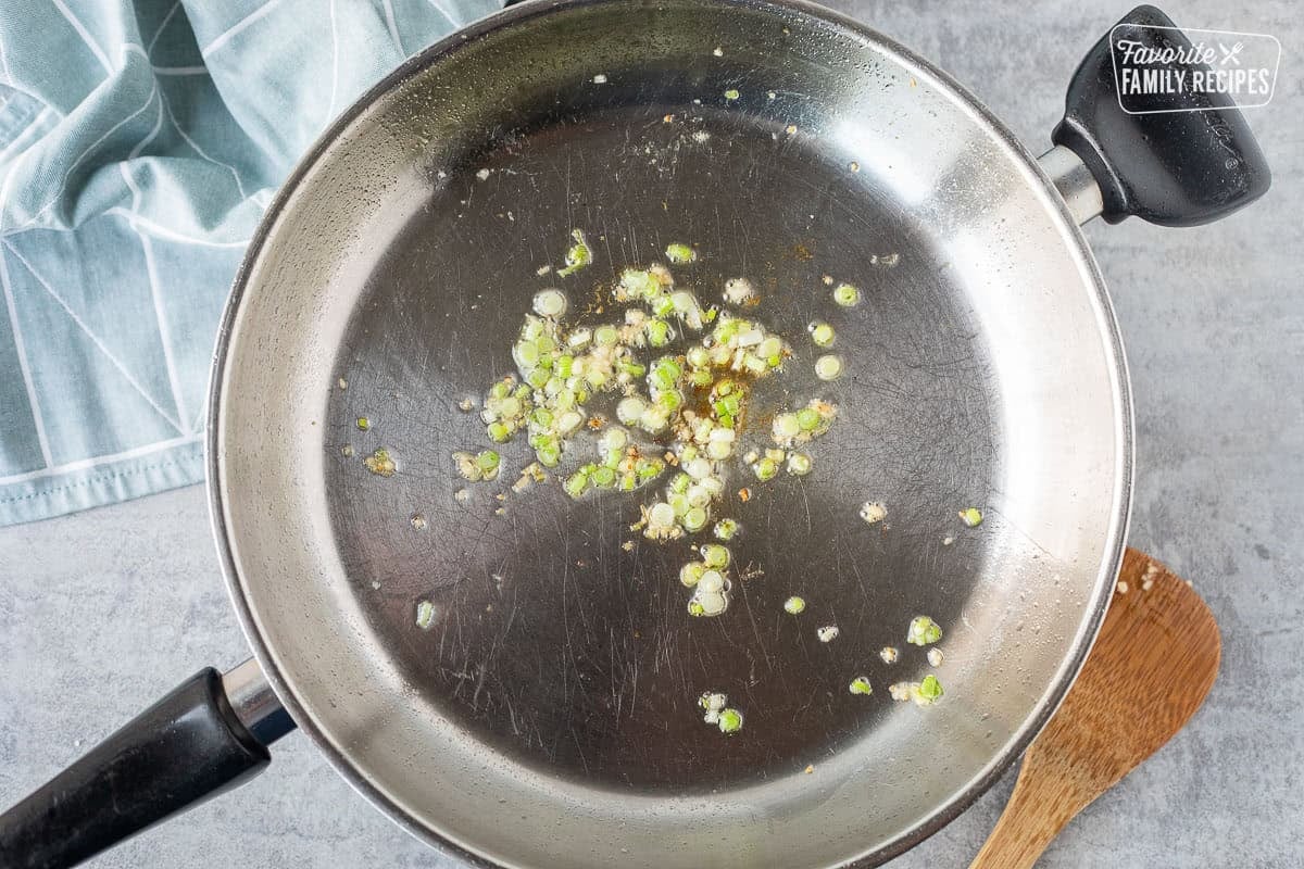 Skillet with sautéed green onions and garlic.