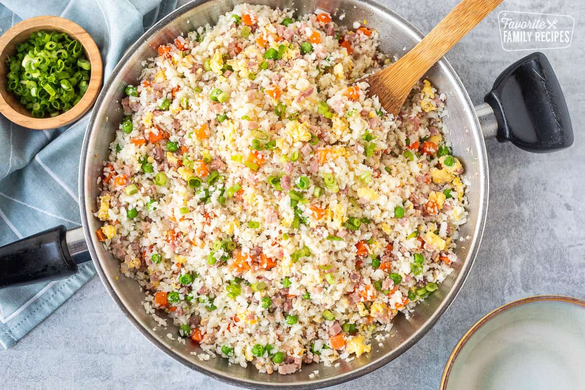 Skillet of cauliflower fried rice and wooden spoon.