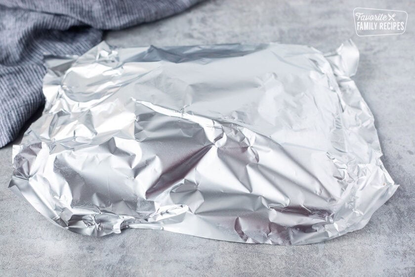 Covering Chipotle steaks with foil on a cutting board.