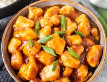 Bowl of Crockpot General Tso's Chicken in a bowl and garnished with green onion.