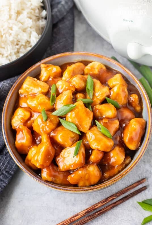 Bowl of Crockpot General Tso's Chicken in a bowl and garnished with green onion.