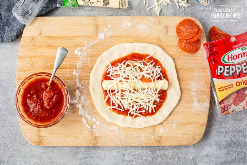 Cheese and toppings on a pizza dough round with marinara sauce.