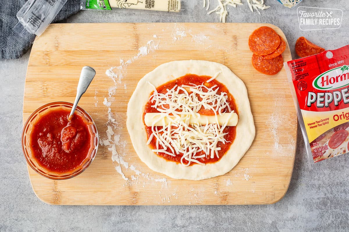 Cheese and toppings on a pizza dough round with marinara sauce.