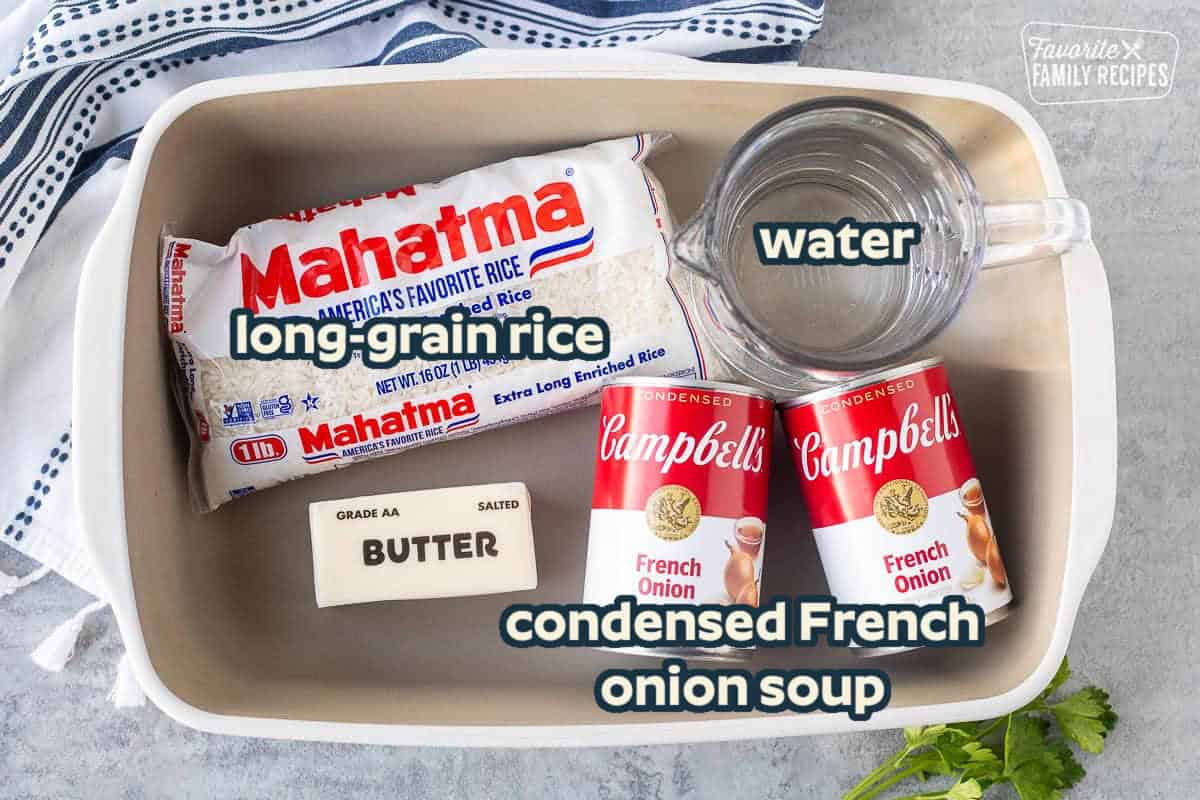 French onion rice ingredients in a casserole dish: white rice, butter, condensed French onion soup, and water